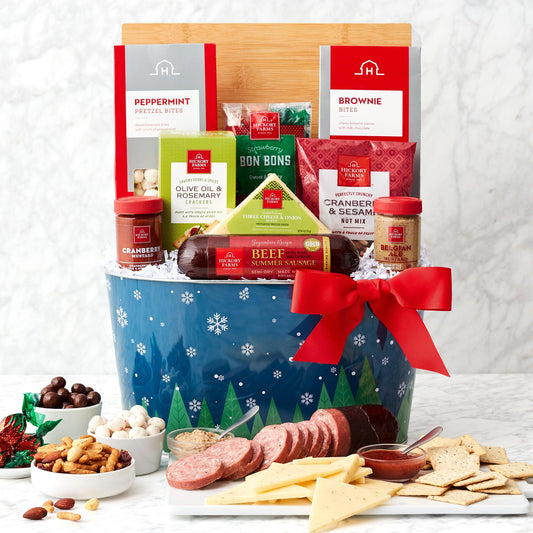 Cozy Christmas Gourmet Gift Basket - Bring cozy feelings of good cheer home with this gourmet holiday gift basket. It’s packed with savory snacks like sausage, cheese, mustards, crackers, and nuts. It’s also full of sweet treats like brownies, candy, and pretzel bites. The included cutting board make serving up sweet and savory snacks a snap.