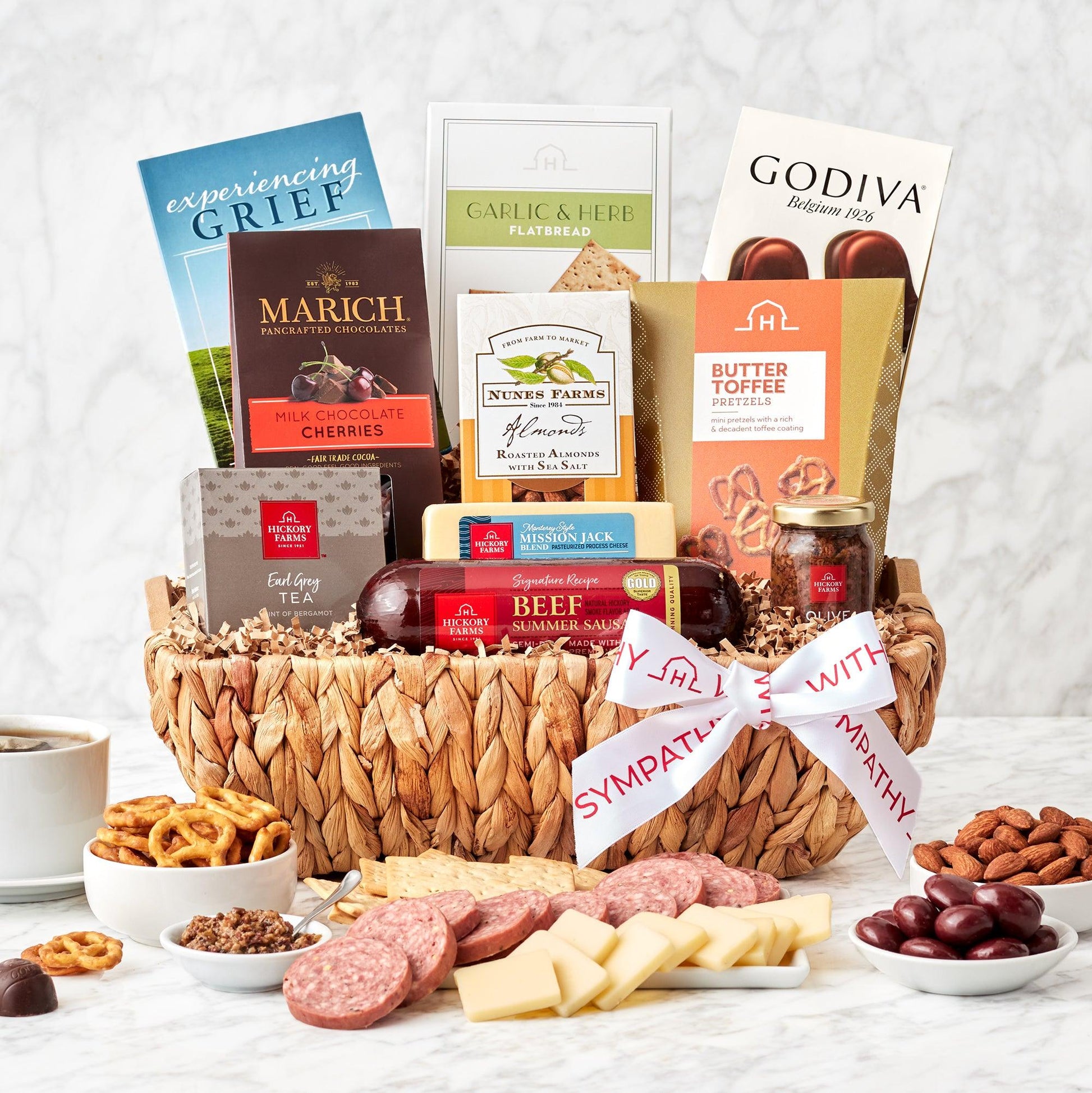 Thoughtful Sympathies Savory Gift Basket - Send a collection of sweet and savory treats to show support to someone going through a tough time. Well-loved flavors are paired deliciously with snacks, treats, and comforting tea. A book called Experiencing Grief adds a thoughtful touch to this gift basket.
